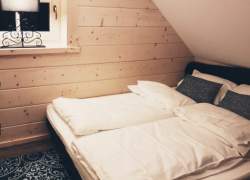 Wnętrze sypialni; drewniane ściany, czarny dywan w biały