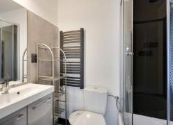 Łazienka, po prawej kabina prysznicowa, na wprost biały sedes, po lewej umywalka, nad nią lustro
