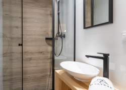 Łazienka w kolorystyce biel, jasny brąz oraz czerń, widoczna umywalka, lustro i kabina prysznicowa