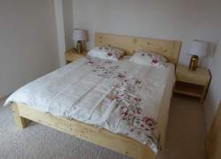 Sypialnia z dużym drewnianym łóżkiem i jasną pościelą w kwiatowy wzór
