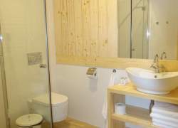 Łazienka w jasnym drewnie - lustro, szafka z półkami, umywalka w kształcie miski - biała), szklana kabina prysznicowa