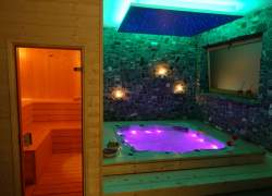 Jacuzzi i sauna, drzwi do sauny otwarte, wewnątrz cieple światło