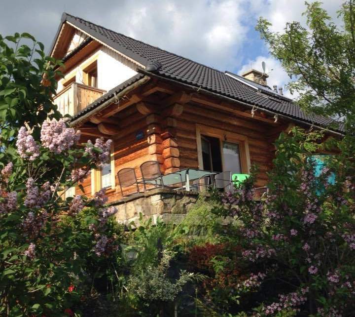 Drewniany dom z bali w letniej scenerii ogrodu