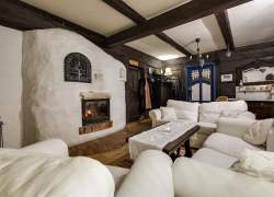 Murowany, pobielony kominek, kanapy i fotele w kolorze bieli