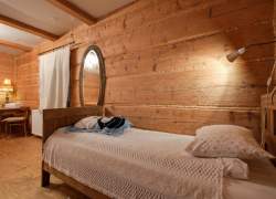 Wnętrze sypialni z drewnianym łóżkiem i owalnym lustrem