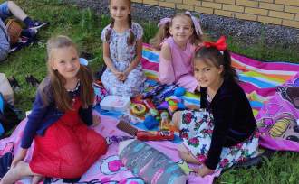 Cztery dziewczynki siedzą na kolorowych kocach, mają ze sobą gry i słodycze