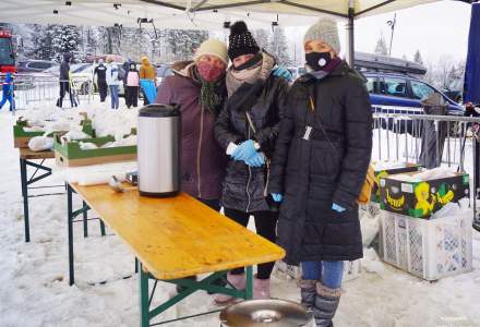 Trzy panie z KGW Jaworzynka  z termosem herbaty przygotowanym do wydawania uczestnikom  biegu, w tle spakowane torebki z prowiantem dla biegaczy