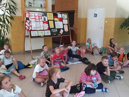 Dzieci siedzące na podłodze w holu szkoły