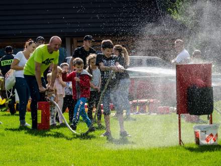 zabawa rodziców z dziećmi z wężem strażackim i tryskającą wodą, wokół dzieci