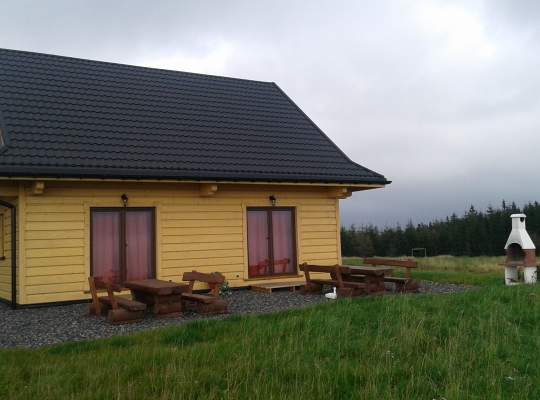 Widok zewnętrzny domku - drewniany, niewielki obiekt, szary dach