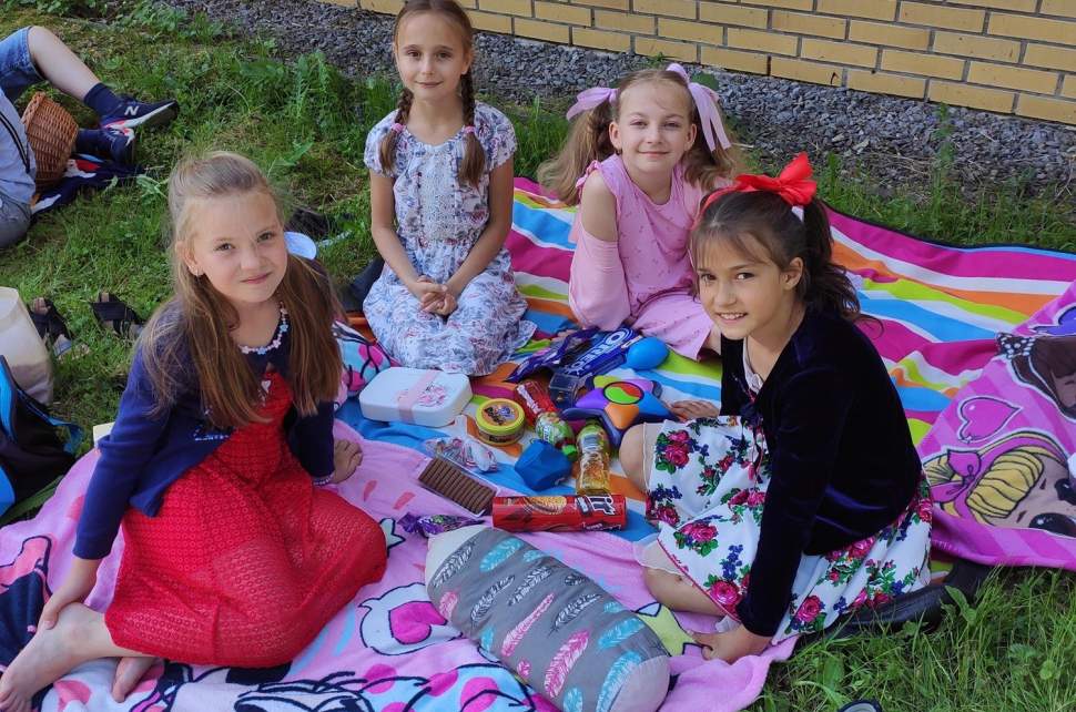 Cztery dziewczynki siedzą na kolorowych kocach, mają ze sobą gry i słodycze